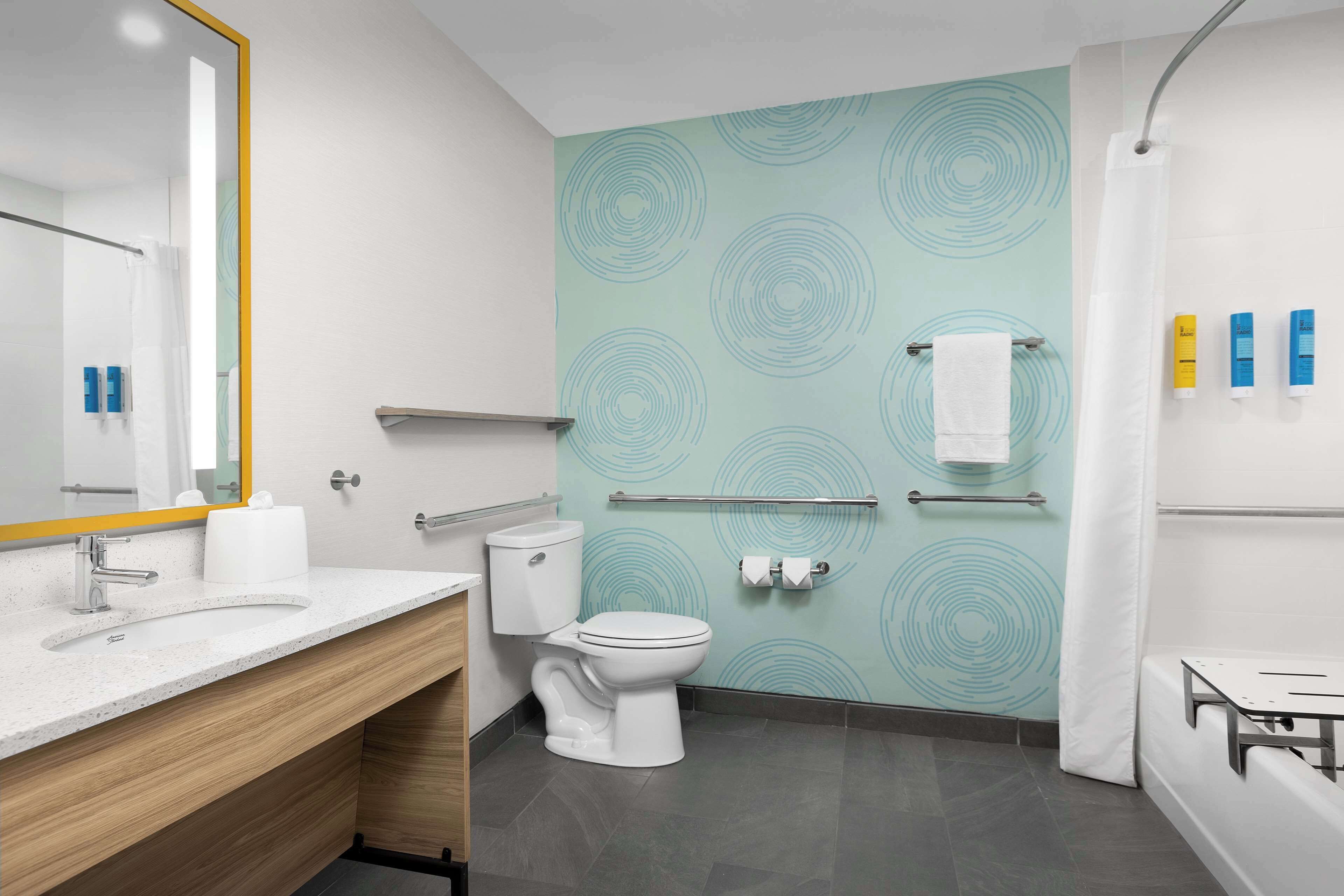 A modern bathroom with a white toilet, a sink with a mirror, a shower area, and a towel rack.
