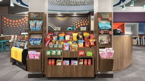 A snack kiosk with a variety of packaged snacks and a sign advertising local items. - Tru by Hilton Jacksonville West I 295 (Jacksonville)