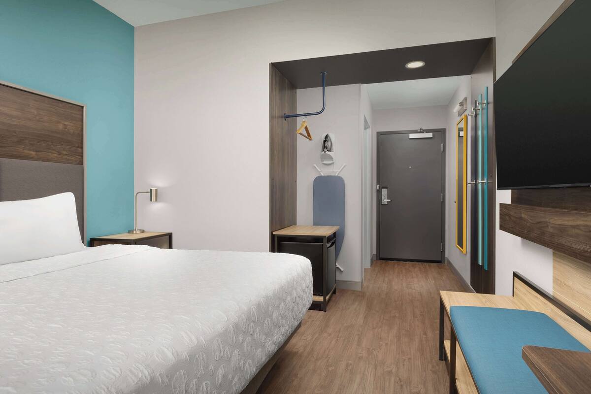 Una habitación de hotel moderna con una cama grande, un escritorio y un banco.