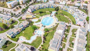An aerial view of a resort with multiple swimming pools, a central circular pool, and a variety of building styles.