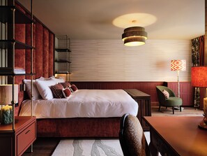Une chambre à coucher avec un grand lit, une table de chevet, une chaise, une bibliothèque et une lampe sur pied.