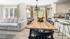 Una cocina moderna con una mesa de comedor de madera, sillas negras y una lámpara colgante.