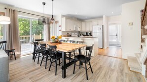 Una cocina moderna con armarios blancos, una isla central y una zona de comedor con mesa de madera y sillas negras.