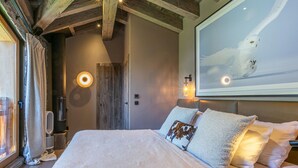 Un dormitorio acogedor con una cama grande, una chimenea y un televisor montado en la pared.