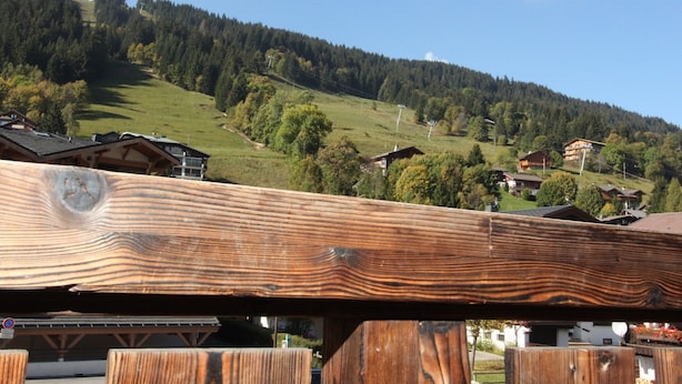A wooden structure with a view of a mountainous landscape and houses in the background. - Cozy Studio for 4 with Balcony, Near Ski Lifts & Village Center (Les Gets)