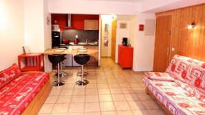 A compact living space with a kitchenette, a dining area with stools, and a sofa. - Cozy Studio for 4 with Balcony, Near Ski Lifts & Village Center (Les Gets)