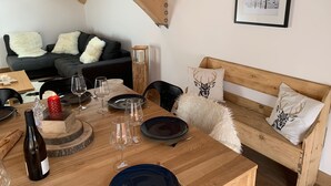 A dining area with a wooden table set for a meal, a sofa with decorative pillows, and a framed picture on the wall. - 4* Chalet for 8, sunny with wifi and pets allowed (Valloire)