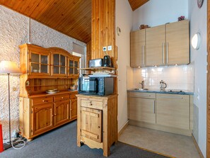 A compact kitchen with wooden cabinets, a microwave, and a sink.