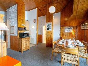 Un coin repas chaleureux, avec des meubles en bois et une table ronde dressée pour quatre personnes.