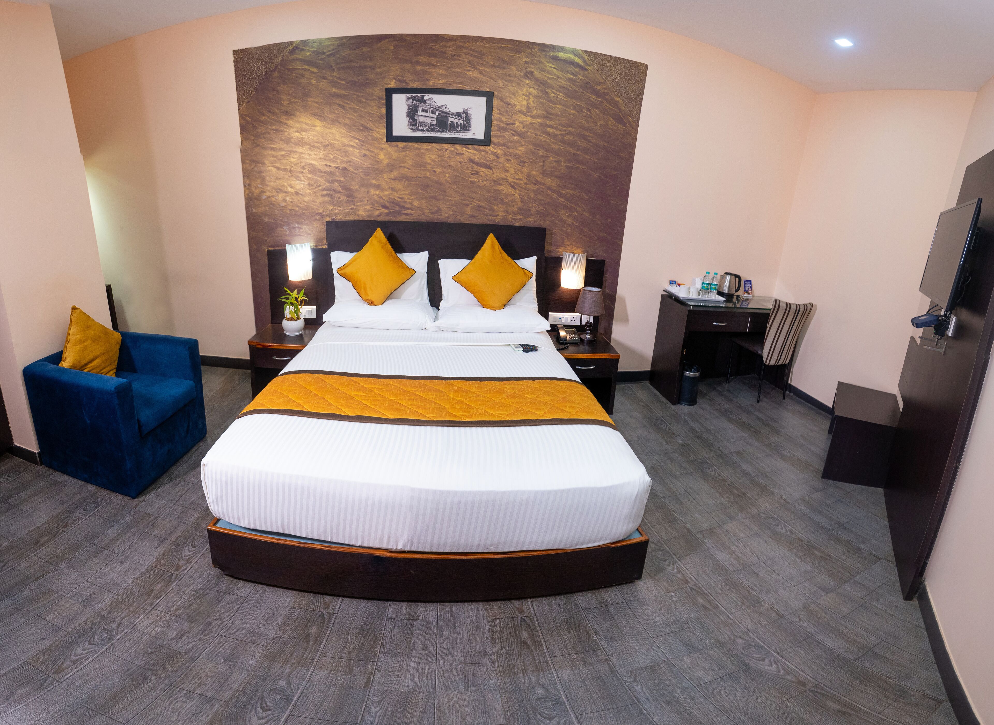 A hotel room with a large bed, a desk, a chair, and a television.