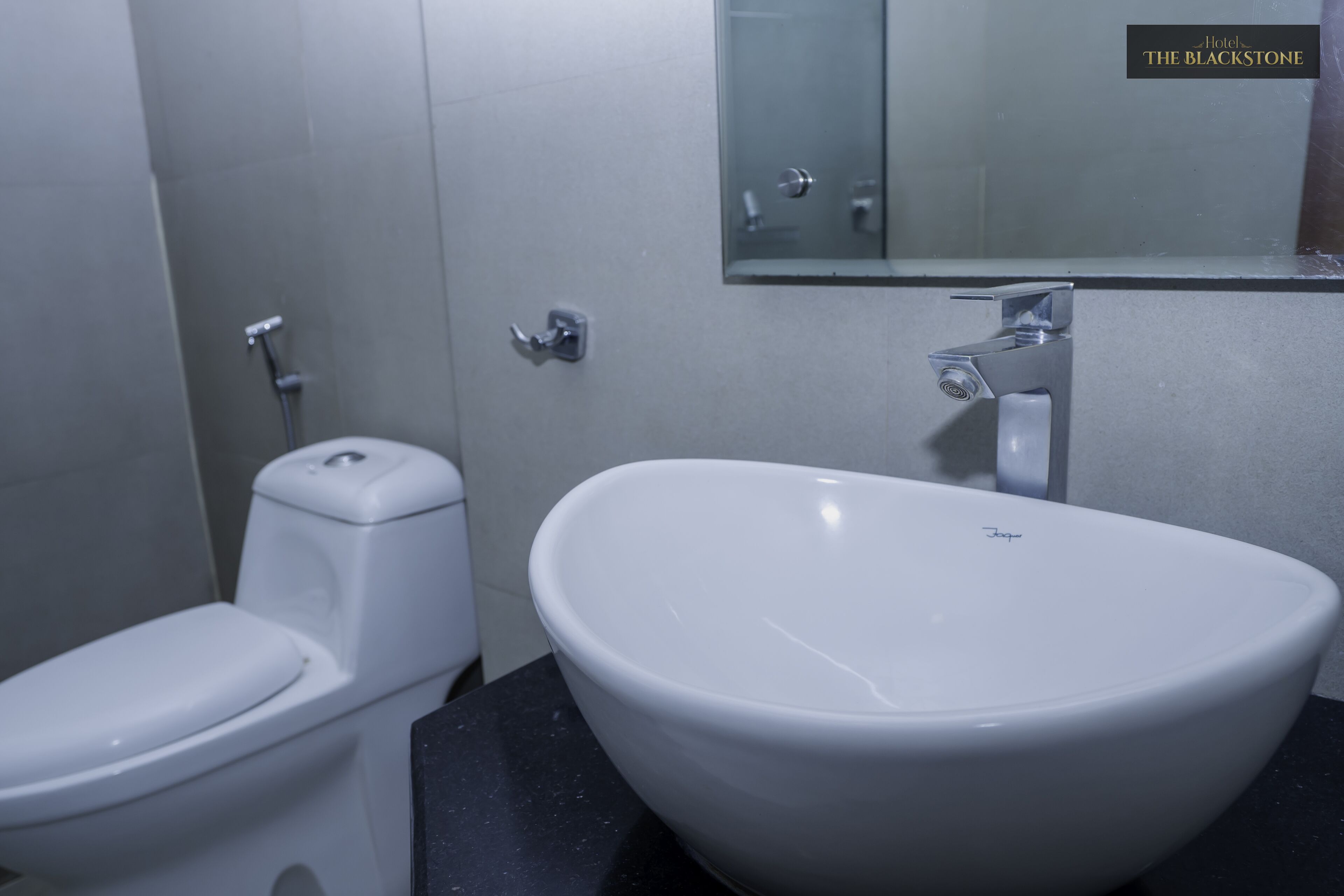Un baño con inodoro blanco, lavabo blanco y espejo sobre el lavabo.