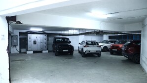 A parking garage with four cars parked in a row. - Hotel The Blackstone (Bengaluru)