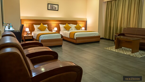 A hotel room with two beds, a sofa, a desk, and a chair. - Hotel The Blackstone (Bengaluru)