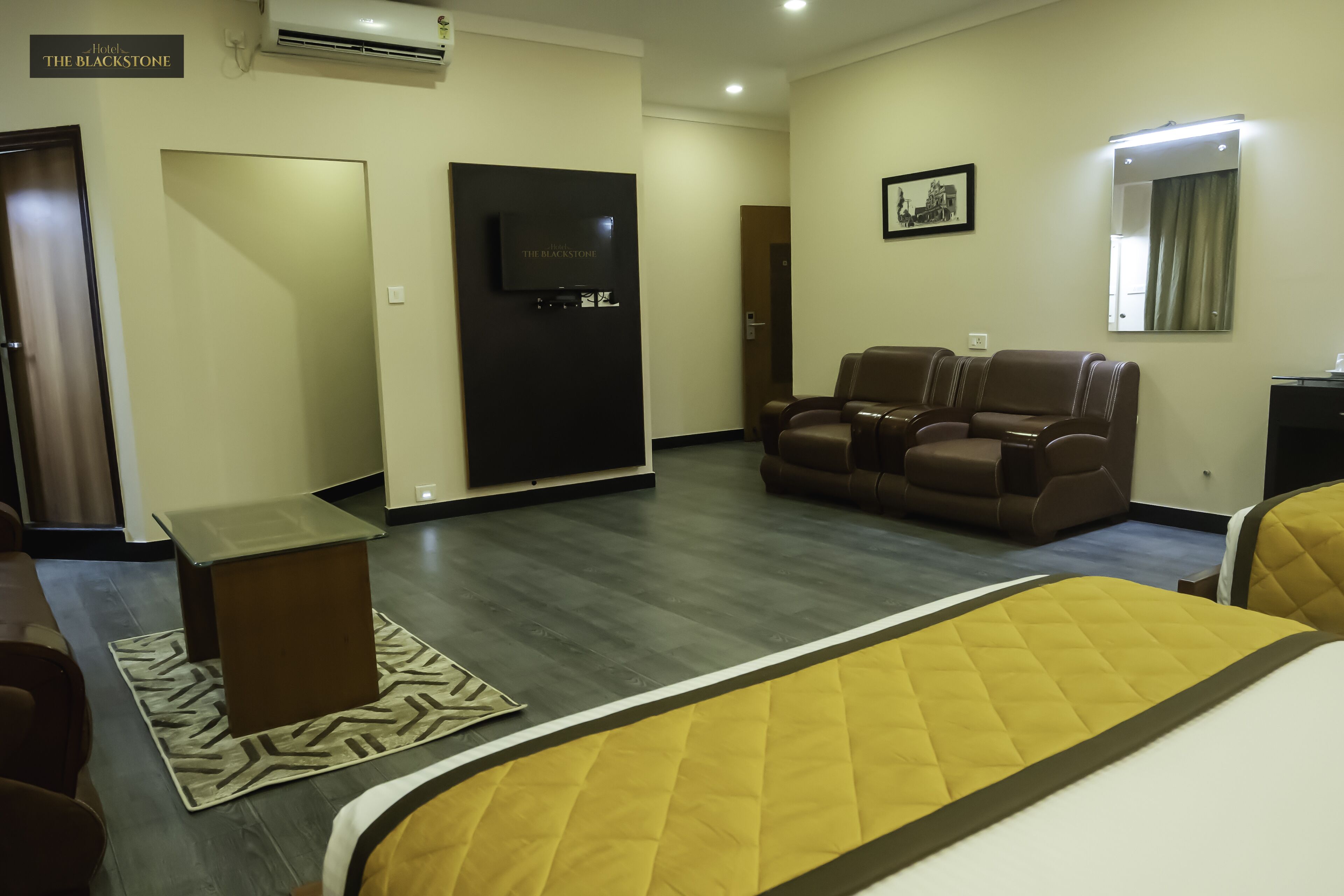 Una habitación de hotel con cama, sofá, televisión y escritorio.