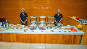 A buffet setup at The Blackstone Hotel with various food items and utensils. - Hotel The Blackstone (Bengaluru)
