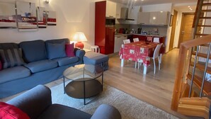 Un saló modern amb un sofà, una taula de centre i una zona de menjador amb taula preparada per a quatre.