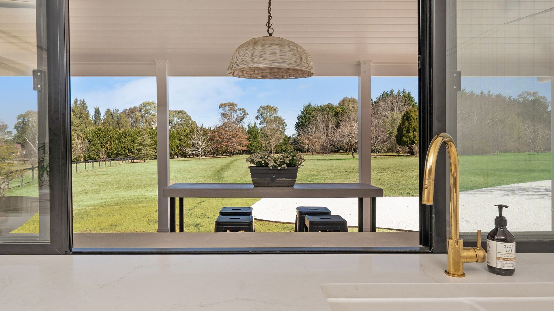 A kitchen with a large window overlooking a grassy area with trees.