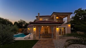 A two-story house with a swimming pool, outdoor seating, and a well-maintained garden.