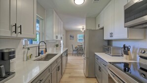 A modern kitchen with white cabinets, stainless steel appliances, and a central island. - River Bend Bliss: Where Memories flow with the River (Cedar Creek)