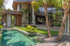 A modern house with a swimming pool, outdoor seating, and a stone facade. - Ohlala : Luxury Tropical Escape in Pererenan (Canggu)