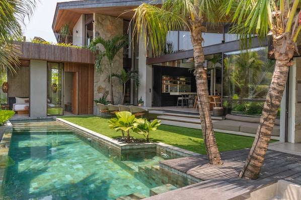 Una casa moderna con piscina, mobiliario exterior y fachada de piedra.