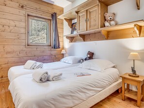 A wooden cabin bedroom with a bed, towels, a lamp, and a teddy bear.
