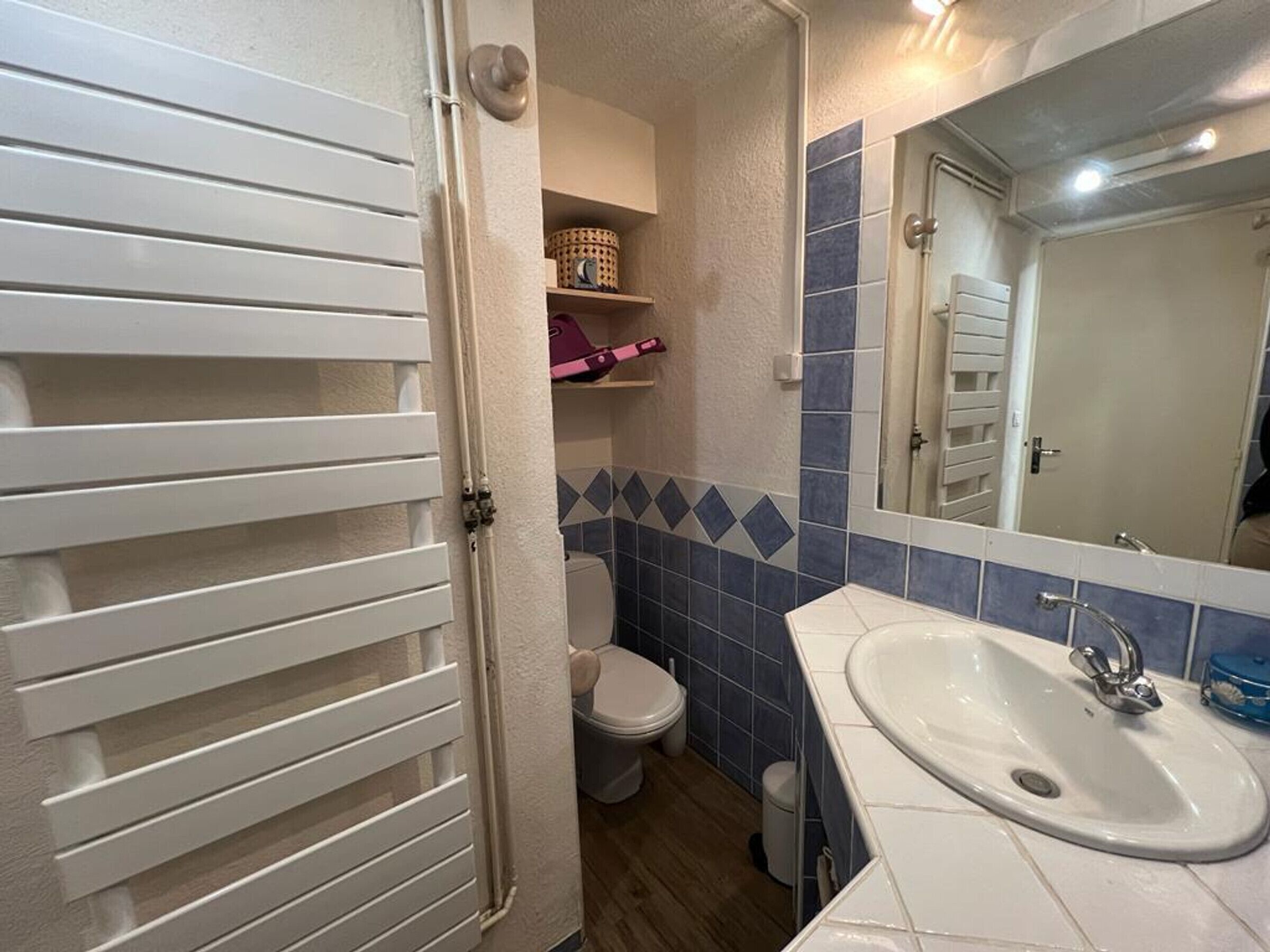 A bathroom with a toilet, a sink, and a mirror.