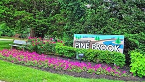 Schild für die Pine Brook Apartments mit angelegtem Garten davor.