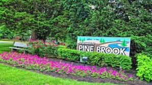 A sign for Pine Brook Apartments with a landscaped garden in the foreground.