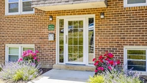 A brick building with a glass door entrance, a mailbox, and a green sign.