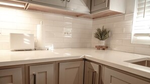 A kitchen with white subway tiles, wooden cabinets, and a countertop. - This apartment is a 1 bedroom(s), 1.5 bathrooms, located in Warwick, Warwick Parish. (Warwick)