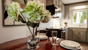 A dining table with a vase of flowers, plates, and cutlery. - This apartment is a 1 bedroom(s), 1.5 bathrooms, located in Warwick, Warwick Parish. (Warwick)