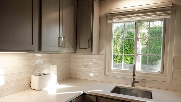 A modern kitchen with white tiles, a built-in toaster, and a window with a view of greenery. - This apartment is a 1 bedroom(s), 1.5 bathrooms, located in Warwick, Warwick Parish. (Warwick)