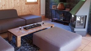 Un salon chaleureux avec un mur en bois, une cheminée, un canapé, une table basse et un tapis.