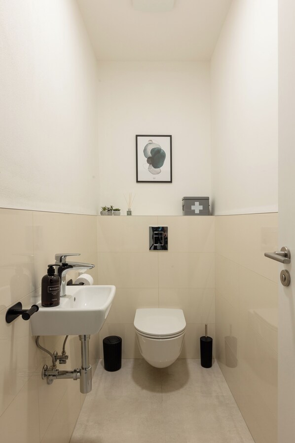 Une petite salle de bain avec un lavabo blanc, des toilettes et un tableau encadré au mur.