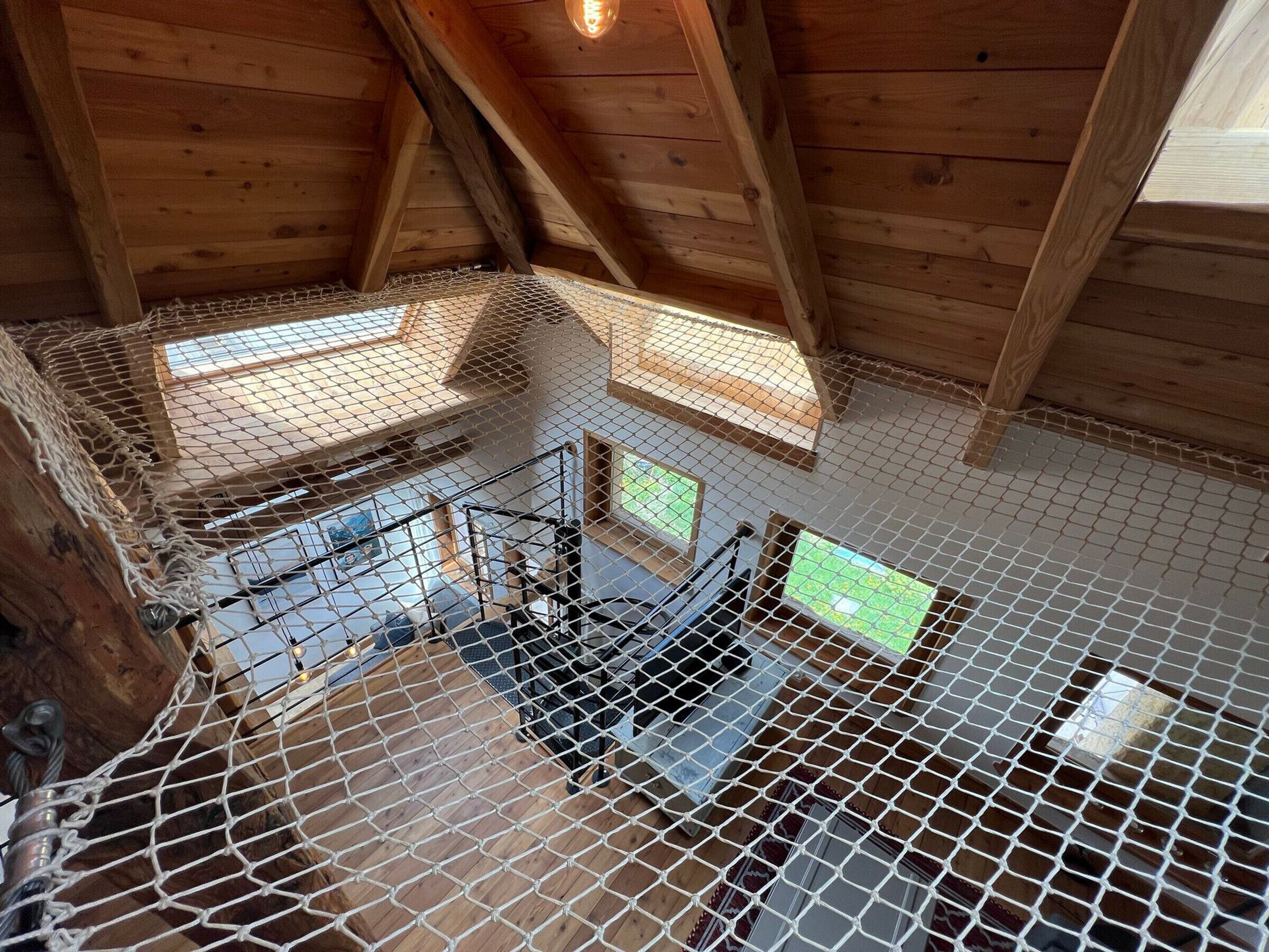 A wooden attic room with a metal mesh floor and a staircase leading to a lower level.