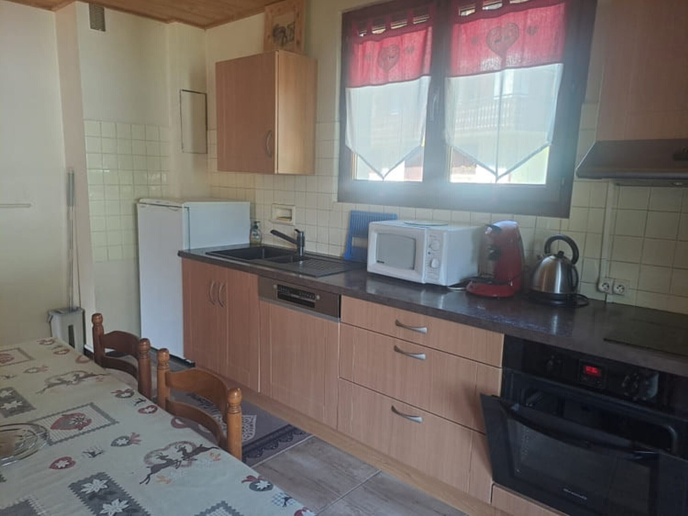 A compact kitchen with a refrigerator, microwave, kettle, and dishwasher.