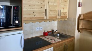 Een keuken met houten kastjes, een magnetron, een fornuis en een spoelbak.