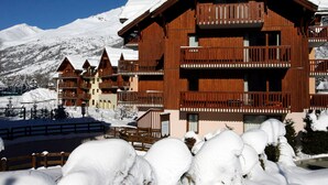 Een houten hotel in chalethuis-stijl met meerdere balkons en een met sneeuw bedekte berg op de achtergrond.