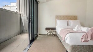 Ein Hotelzimmer mit Bett, Nachttisch und Blick nach draußen.
