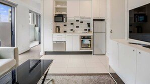 Eine moderne Küche mit weißen Schränken, einer Mikrowelle, einem Backofen und einem großen Fenster.