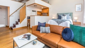 Un salon moderne avec un canapé, une table basse et un lit avec des coussins.