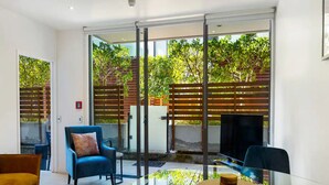 A modern living room with a glass table, blue armchairs, and a TV. - Charming 1BR in Wynyard Quarter I Zodiak Stays (Auckland)