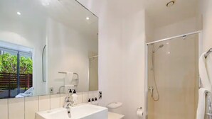 A modern bathroom with a large mirror, a sink, a toilet, and a glass-enclosed shower. - Charming 1BR in Wynyard Quarter I Zodiak Stays (Auckland)