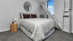Une chambre à coucher avec un lit, un miroir rond, une table de chevet et un escalier.