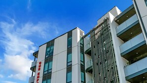 Un bâtiment moderne avec une enseigne verticale bien visible, dont les lettres sont de couleur rouge.
