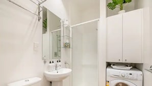 A compact bathroom with a toilet, sink, and built-in washing machine.