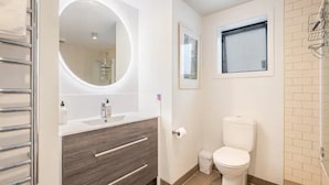 A modern bathroom with a vanity, toilet, and a window. - Stylish And Serene Living In Kohimarama (Auckland)