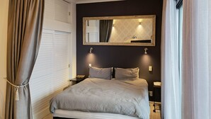 A bedroom with a bed, bedside tables, a mirror, and curtains. - Viaduct apartment with a balcony by Zodiak Stays (Auckland)