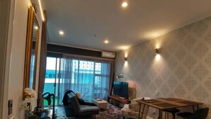 A modern living room with a sofa, a TV, a dining table, and a large window with curtains. - Viaduct apartment with a balcony by Zodiak Stays (Auckland)